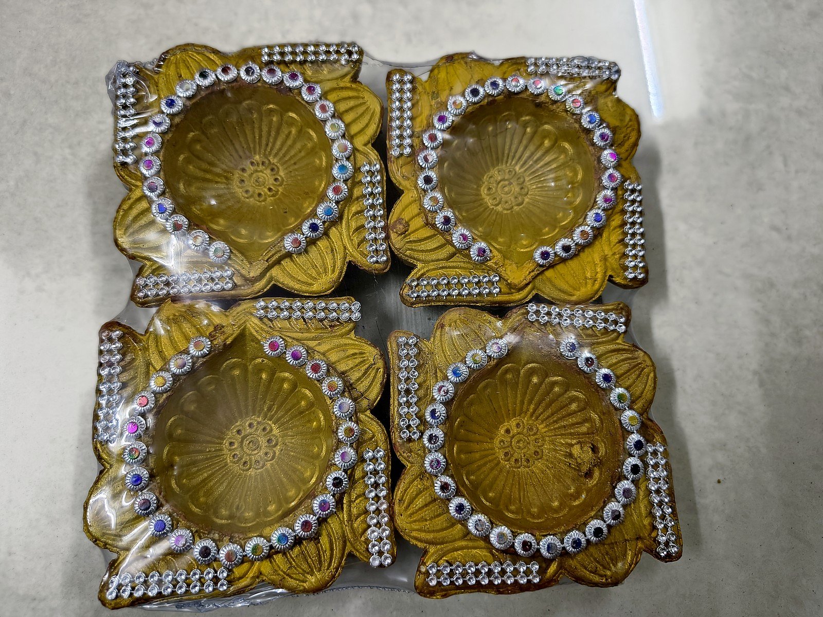 Four golden clay diyas with stone and mirror work
